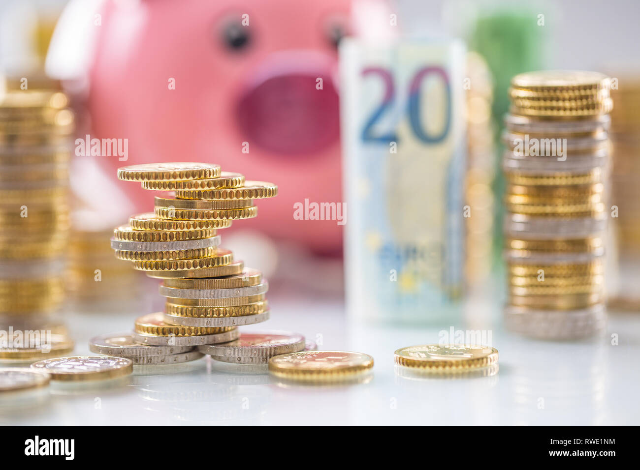Pink piggy bank in the middle of rolled euro banknotes and towers with ...