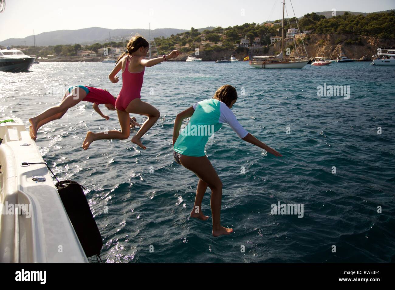 Kids jump from boat into mediterranean sea Stock Photo