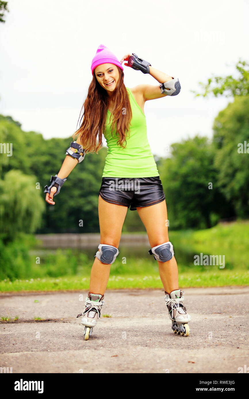 Happy young girl enjoying roller skating rollerblading on inline skates sport in park. Woman in outdoor activities Stock Photo