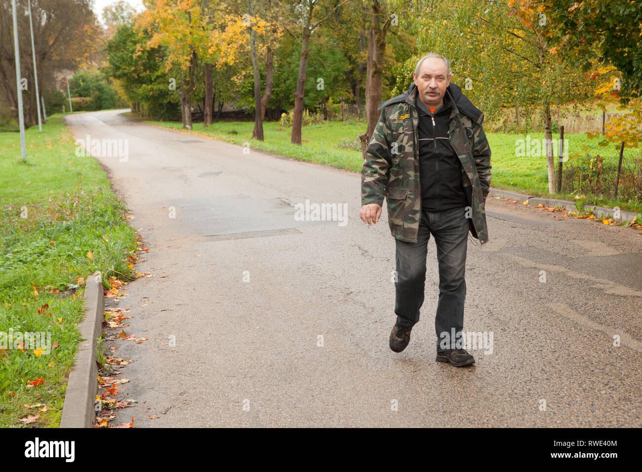 Latvian man walking along suburban road, Skrunda, Latvia Stock Photo