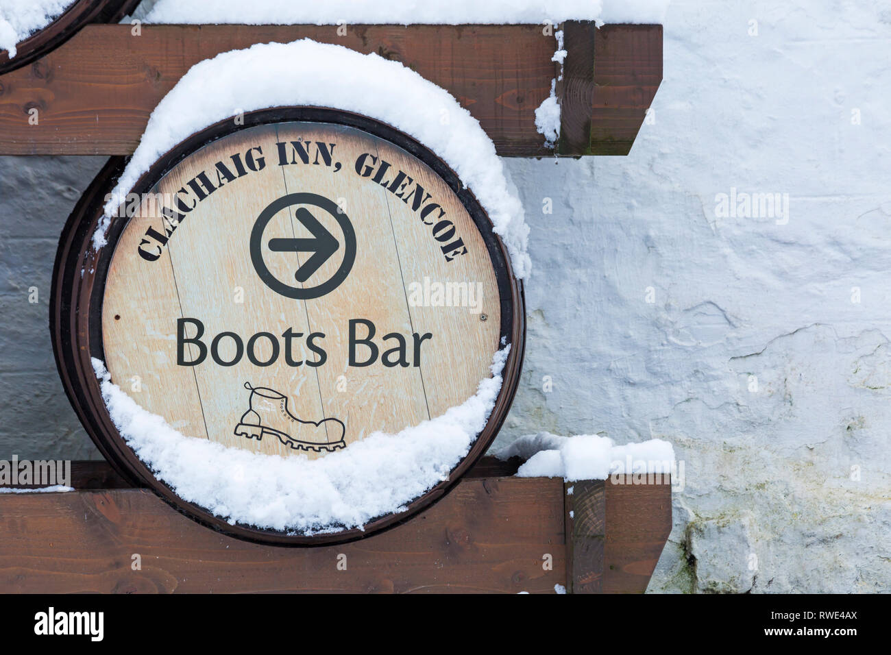 Boots Bar sign on whisky barrel outside Clachaig Inn in the snow at Clachaig Inn, Glencoe, Argyll & Bute, Highlands, Scotland in Winter Stock Photo