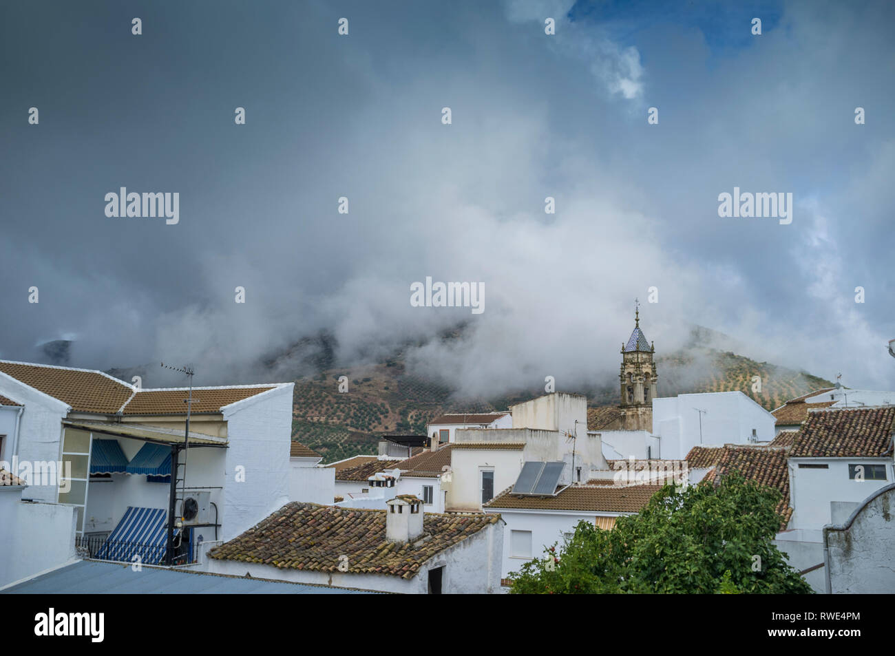 The early morning clouds are down over the mountains and the small town of Carcabuey in the Sierras Subbeticas, Andalusia, Spain Stock Photo