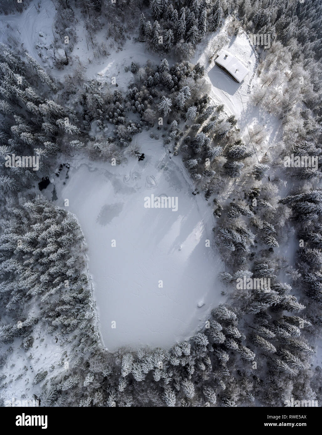 Amazing drone shot overlooking a frozen lake and forest high in the alps of France. Stock Photo