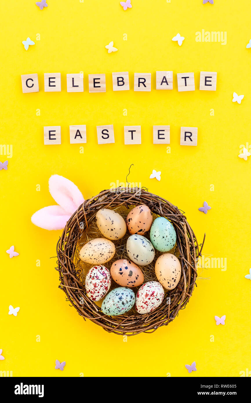 Creative Top view flat lay holiday composition Easter bunny ears eggs text message on bold yellow paper background copy space Template Easter day seas Stock Photo