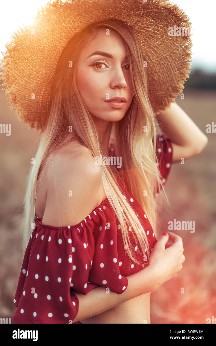 Beautiful woman in red dress and straw hat, summer on wheat field ...