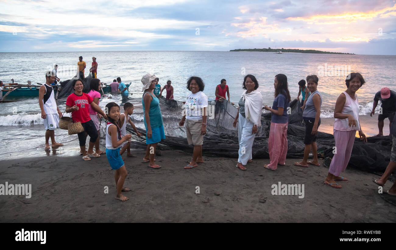 Community Women and Men Cooperating to Pull Fishing Net From Sea - Antique, Philippines Stock Photo