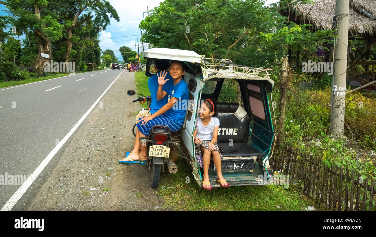 Tricycle With Student passenger girls Waving from back - Antique, Philippines Stock Photo