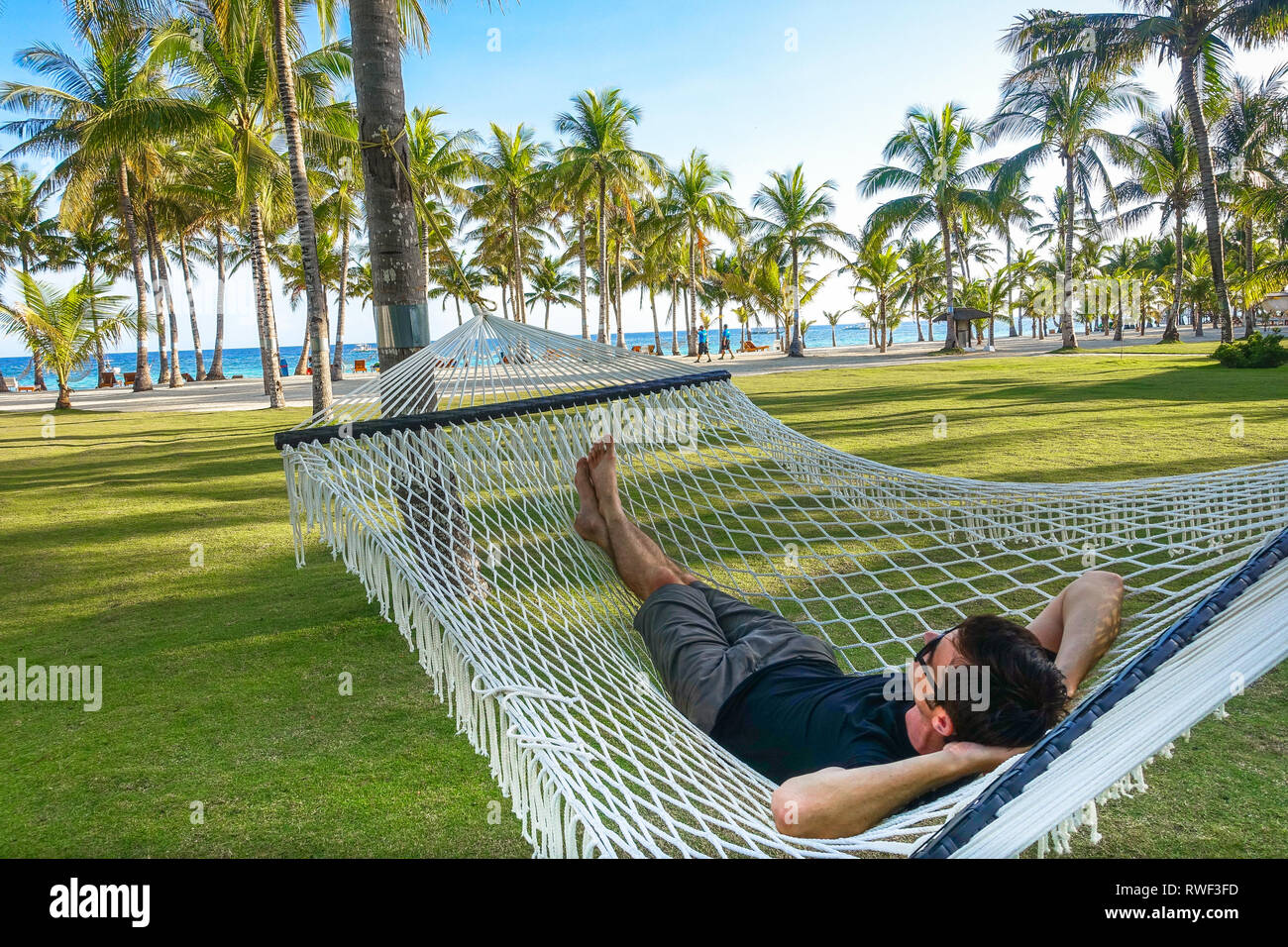 Tourist Man Relaxing in Large Rope Hammock, Panglao - Bohol, Philippines Stock Photo