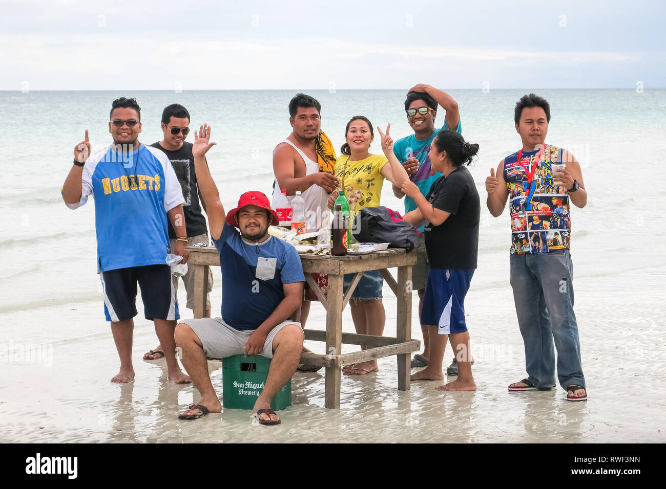 Filipino Friends Having a Food and Drink Picnic in shallow water of Sugar Beach, Bantayan Island - Cebu, Philippines Stock Photo