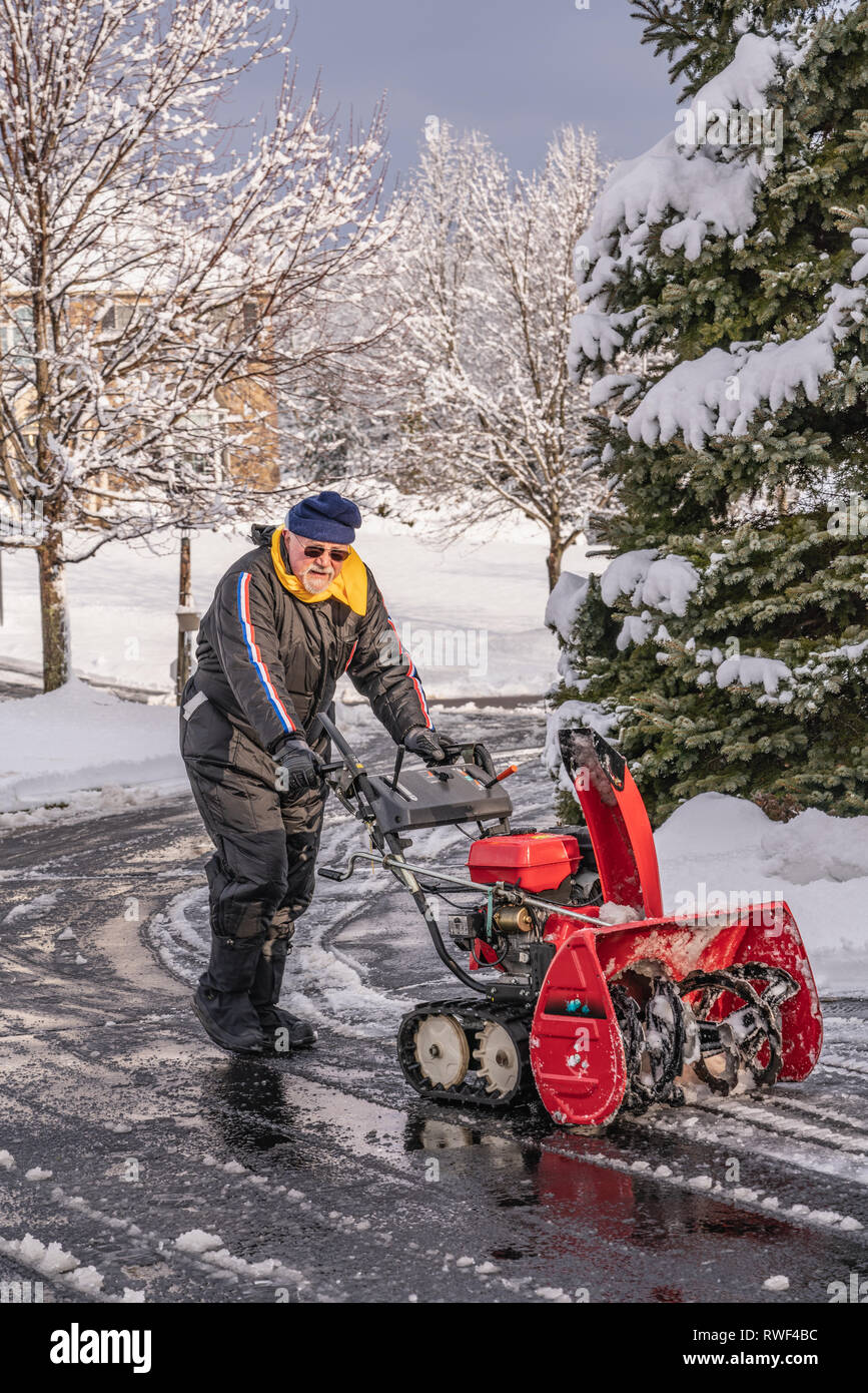 senior citizen with snow blower after clearing driveway of snow from a