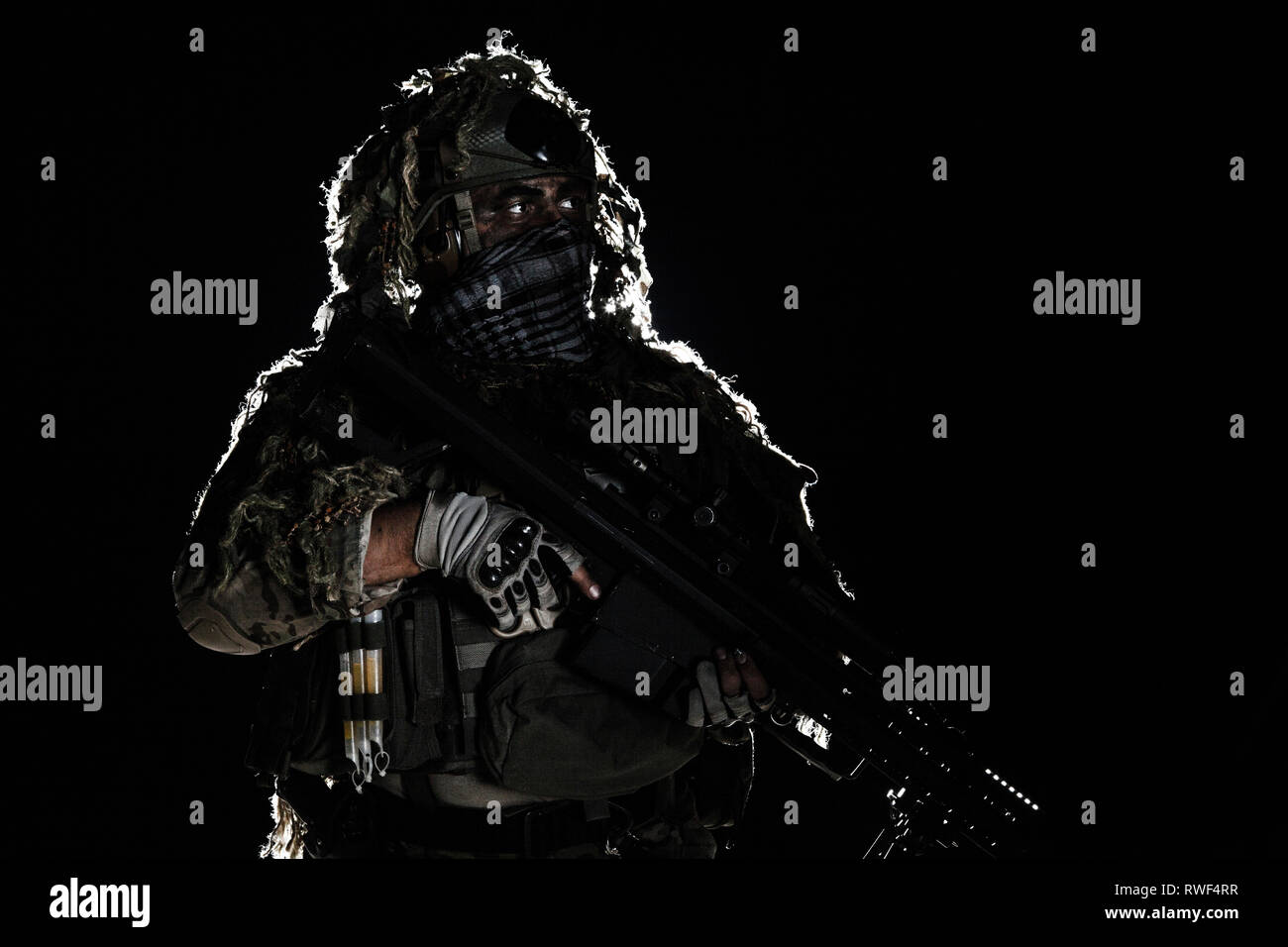 Army sniper with painted face, holding a big rifle. Stock Photo