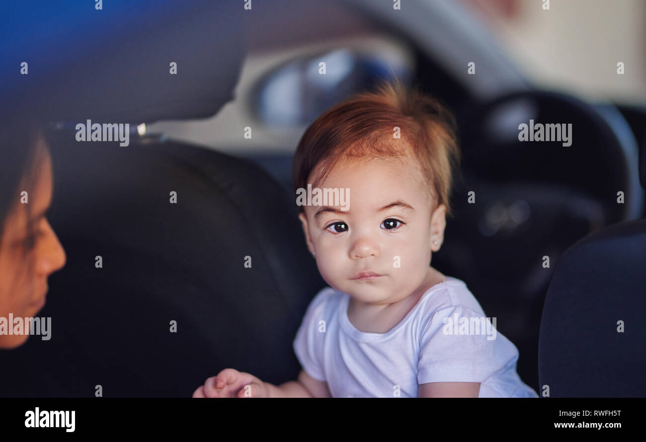 Unhappy baby girl in car on wheel background Stock Photo
