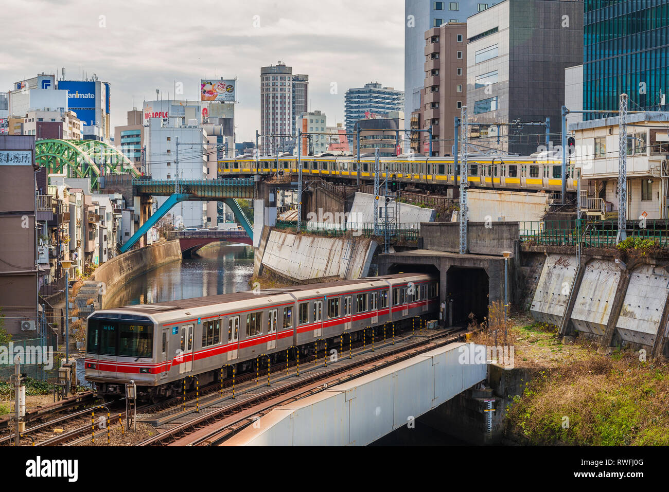 Train junction near Ochanomizu Railway Station and River Kanda in Tokyo, with Marunouchi Subway Line and Chou Railway Line passing at the same time Stock Photo