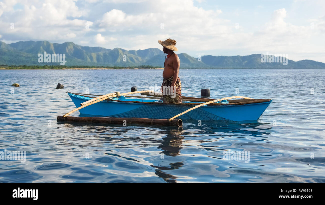 Fisherman in Sun hat, standing in small blue boat - Tibiao, Antique -  Philippines Stock Photo - Alamy