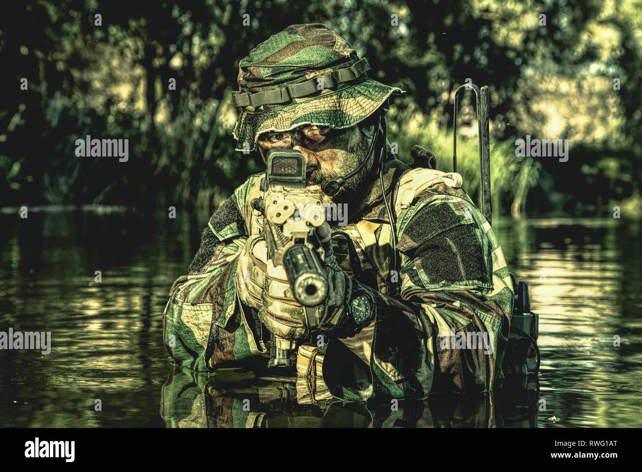 Bearded soldier pointing rifle to camera during a river raid in the ...