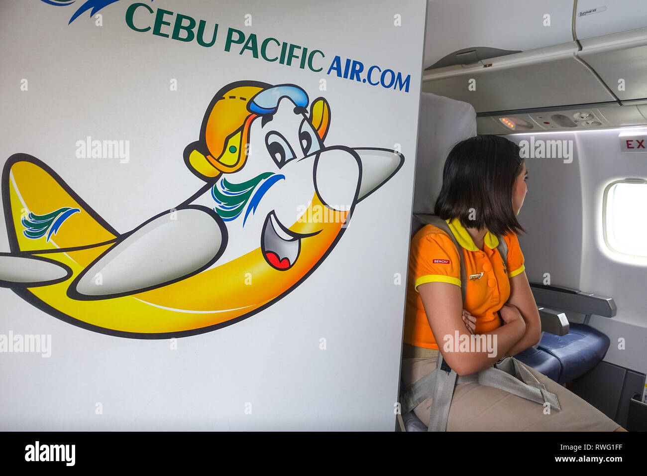 Young Flight Attendant Woman in Plane Window Seat, With Cebu Pacific Airline Logo Stock Photo