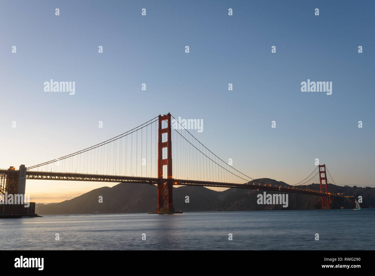 Towers of the Golden Gate Bridge rise above the water at dusk Stock Photo