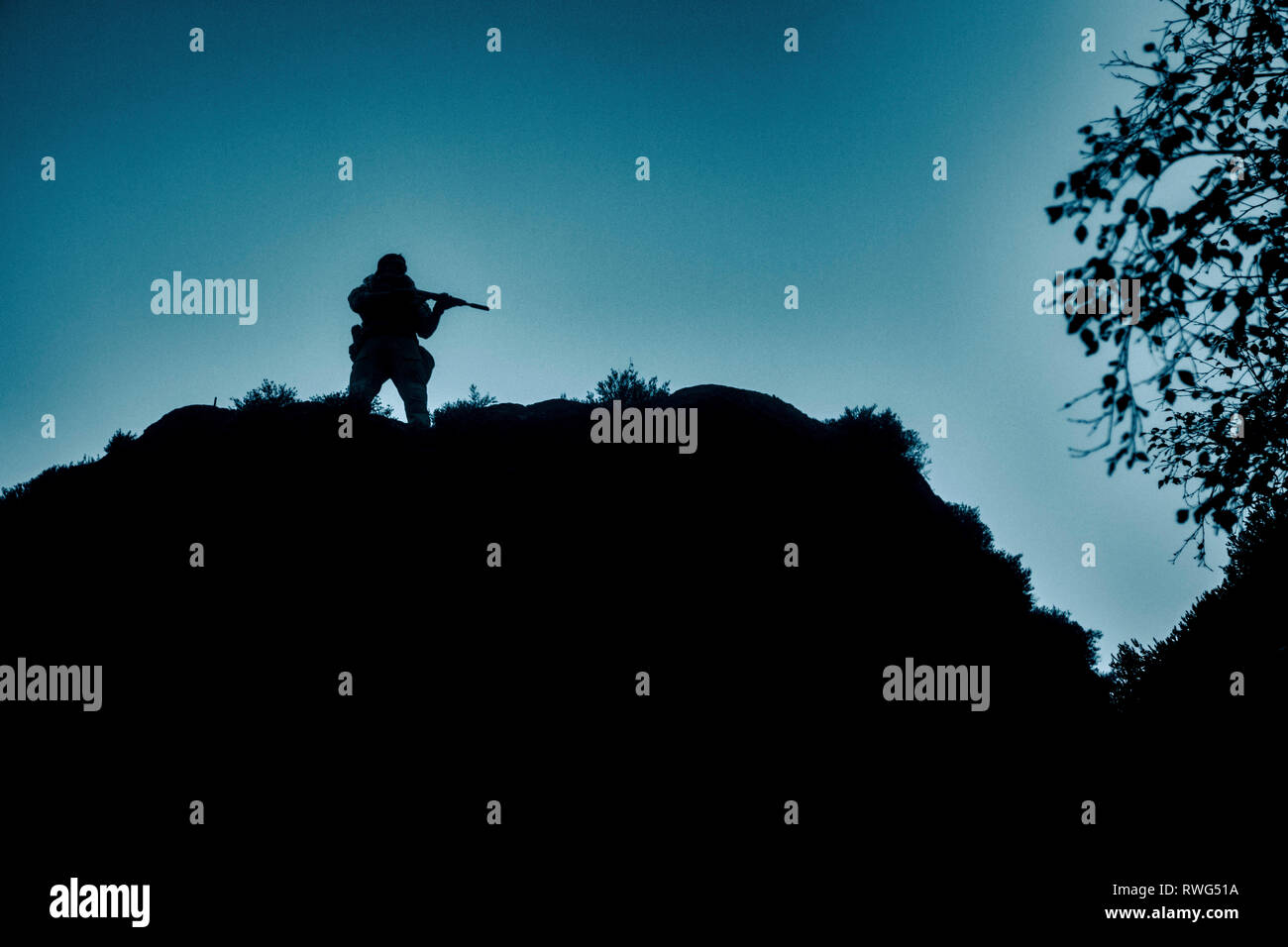 Silhouette of a private military contractor atop a hill. Stock Photo