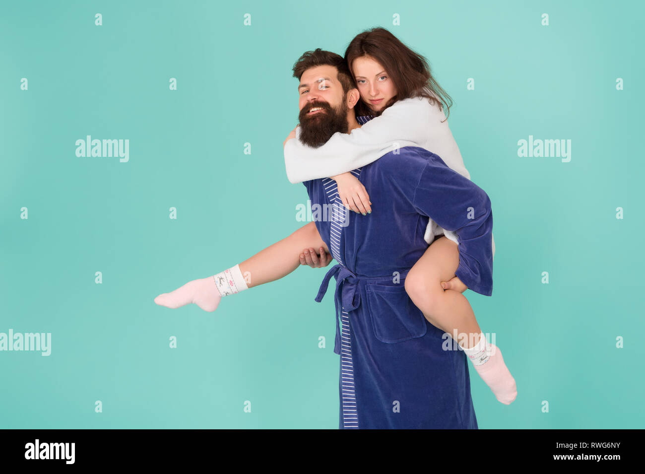 Couple in bathrobes having fun turquoise background. Lets stay at home and have fun. They always