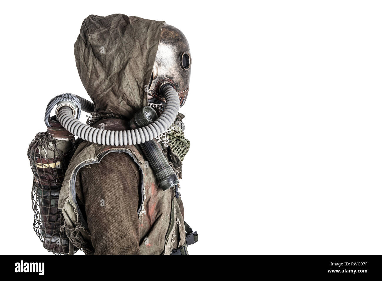 Scary post apocalyptic survivor wearing full-face gas mask under tattered hood. Stock Photo