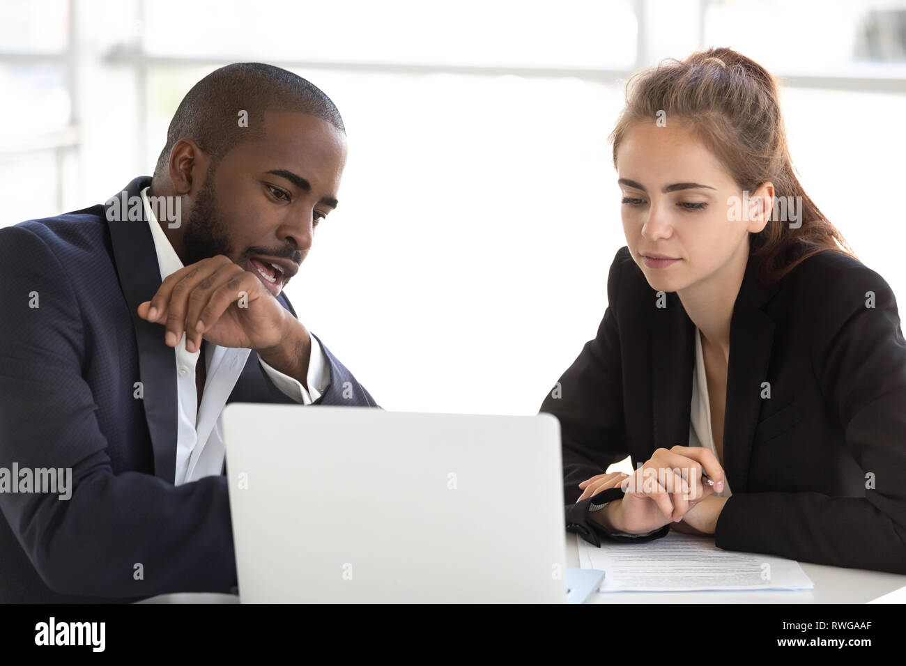 Multiracial millennial team working together in office using laptop Stock Photo