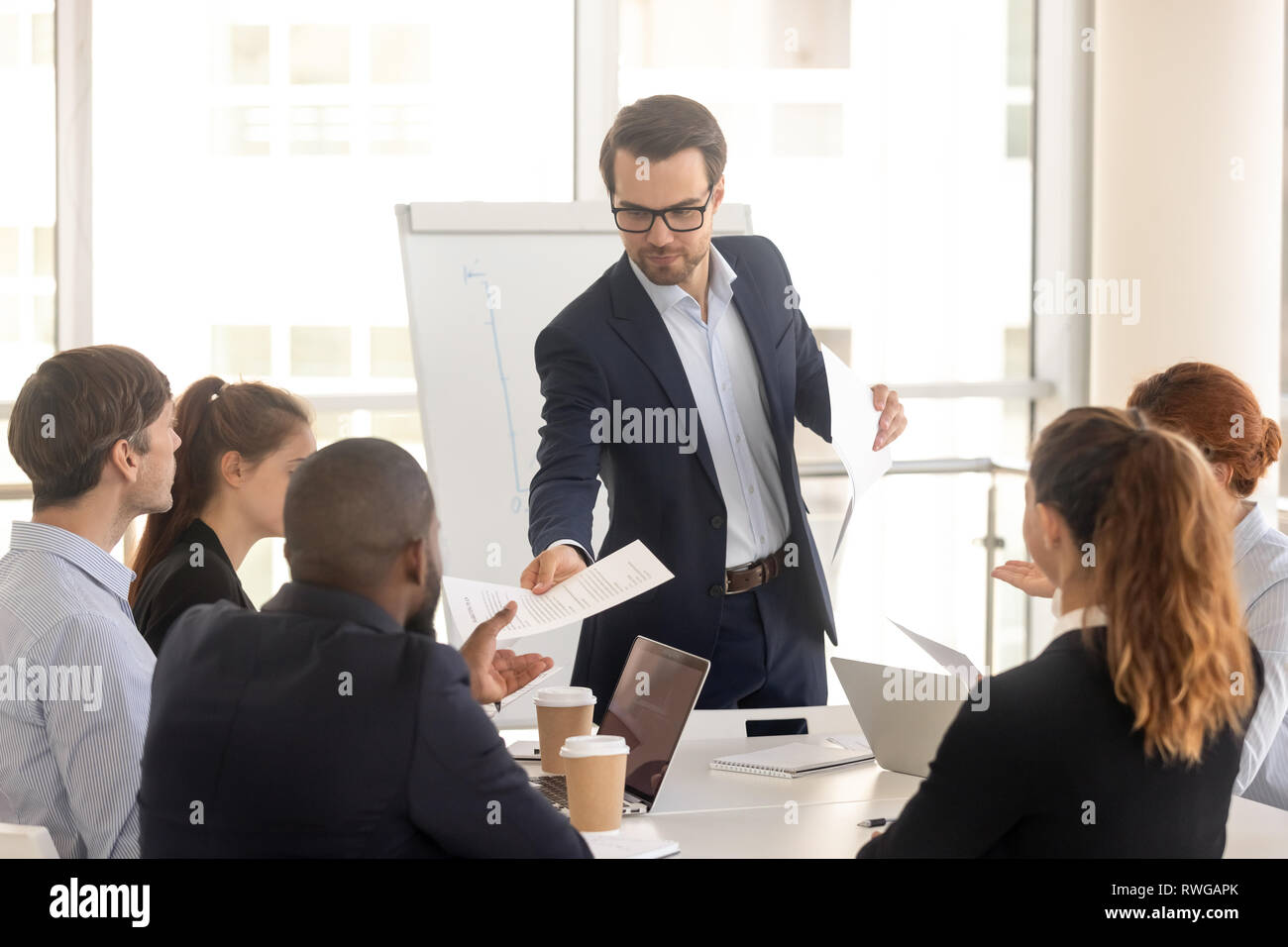 Confident coach giving handout to diverse seminar participants Stock ...