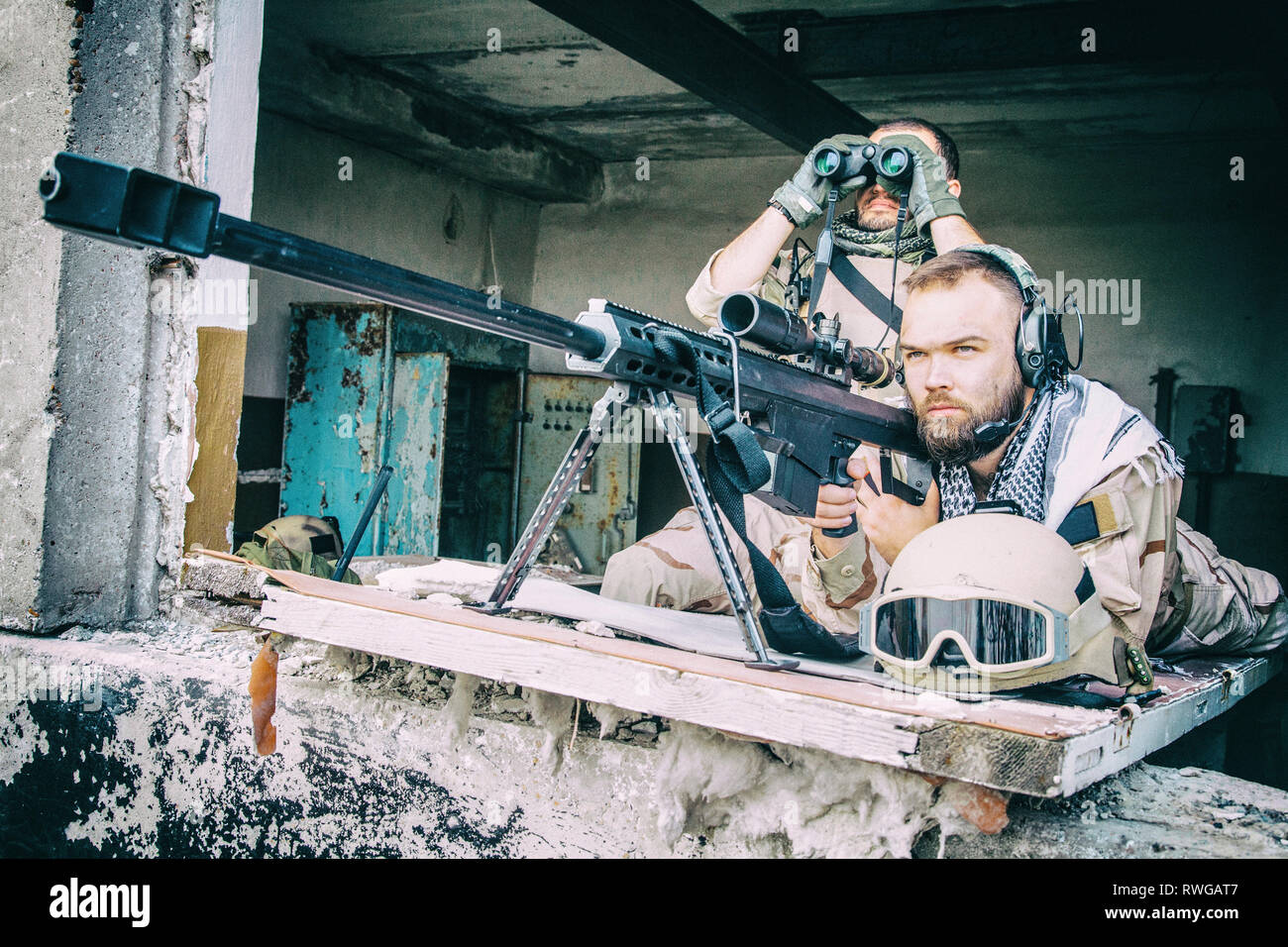 A U.S. paratrooper scans for targets behind a Barrett .50-caliber sniper  rifle while on a