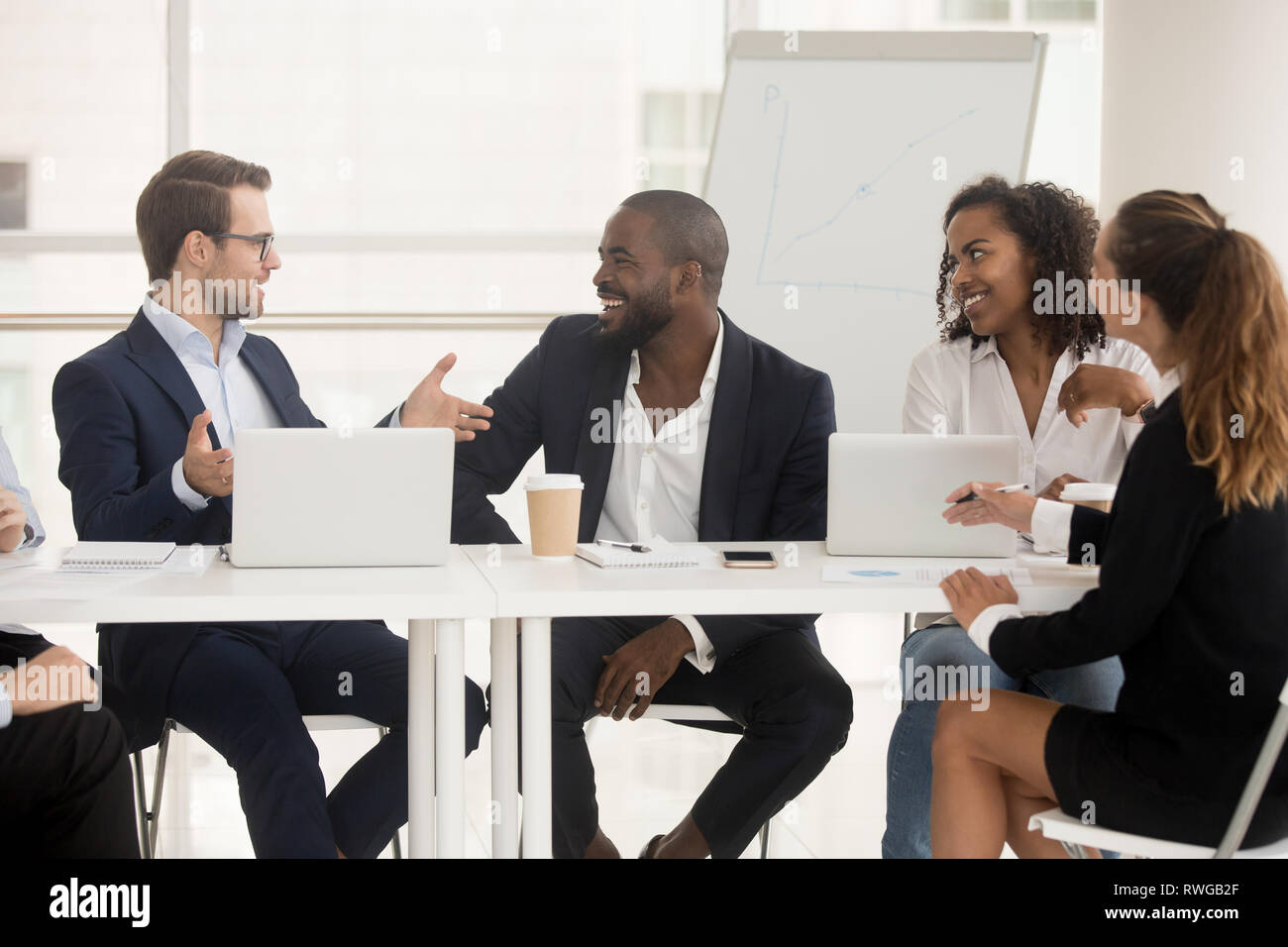 Multiracial employees sitting at boardroom desk listening team leader Stock Photo