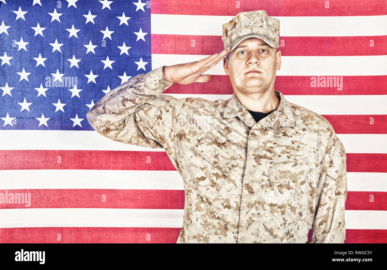 Portrait of U.S. soldier in camouflage uniform saluting American flag. Stock Photo