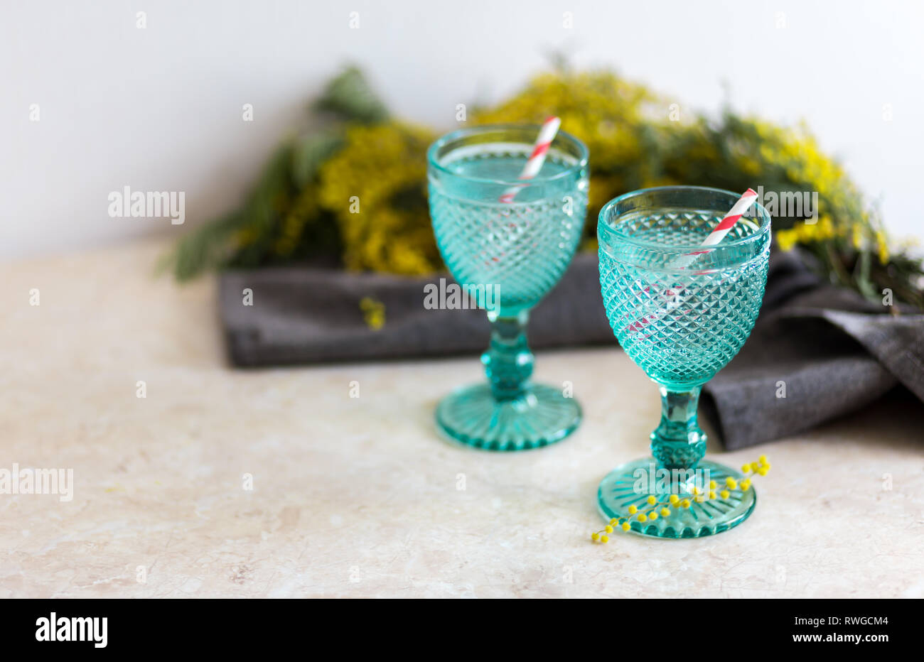 Refhesing drink in blue vintage goblets on the white background with srping flowers. Mimosa flowers Stock Photo