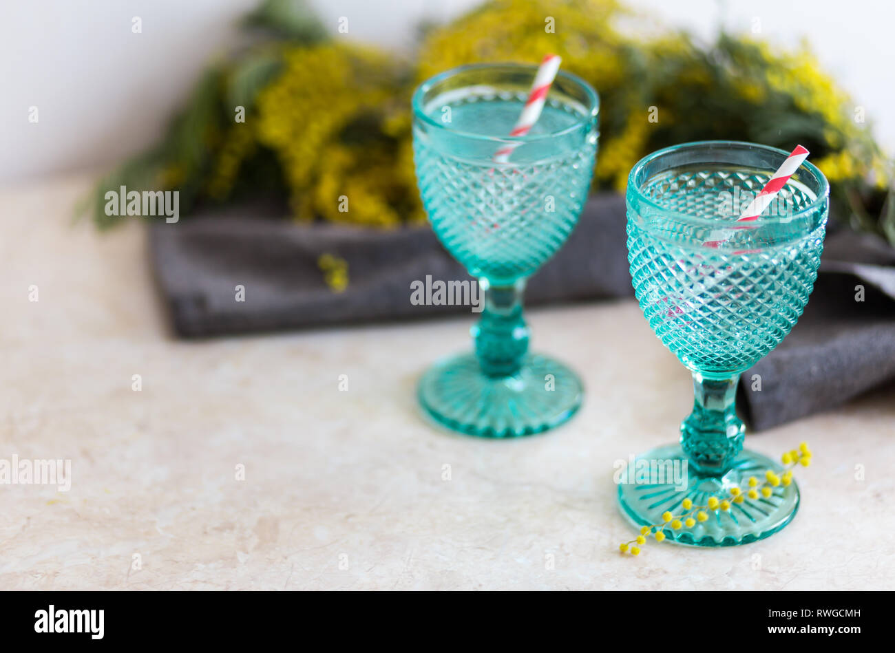 Refhesing drink in blue vintage goblets on the white background with srping flowers. Mimosa flowers Stock Photo