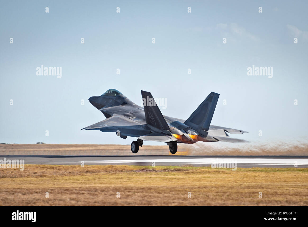 US Air Force F-22 Raptor in flight,taking off with flames from engines, landing gear visible Stock Photo