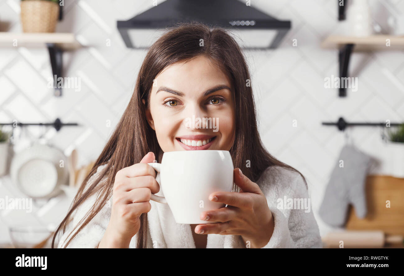 Brunette woman smiling at the kitchen with white cup Stock Photo - Alamy