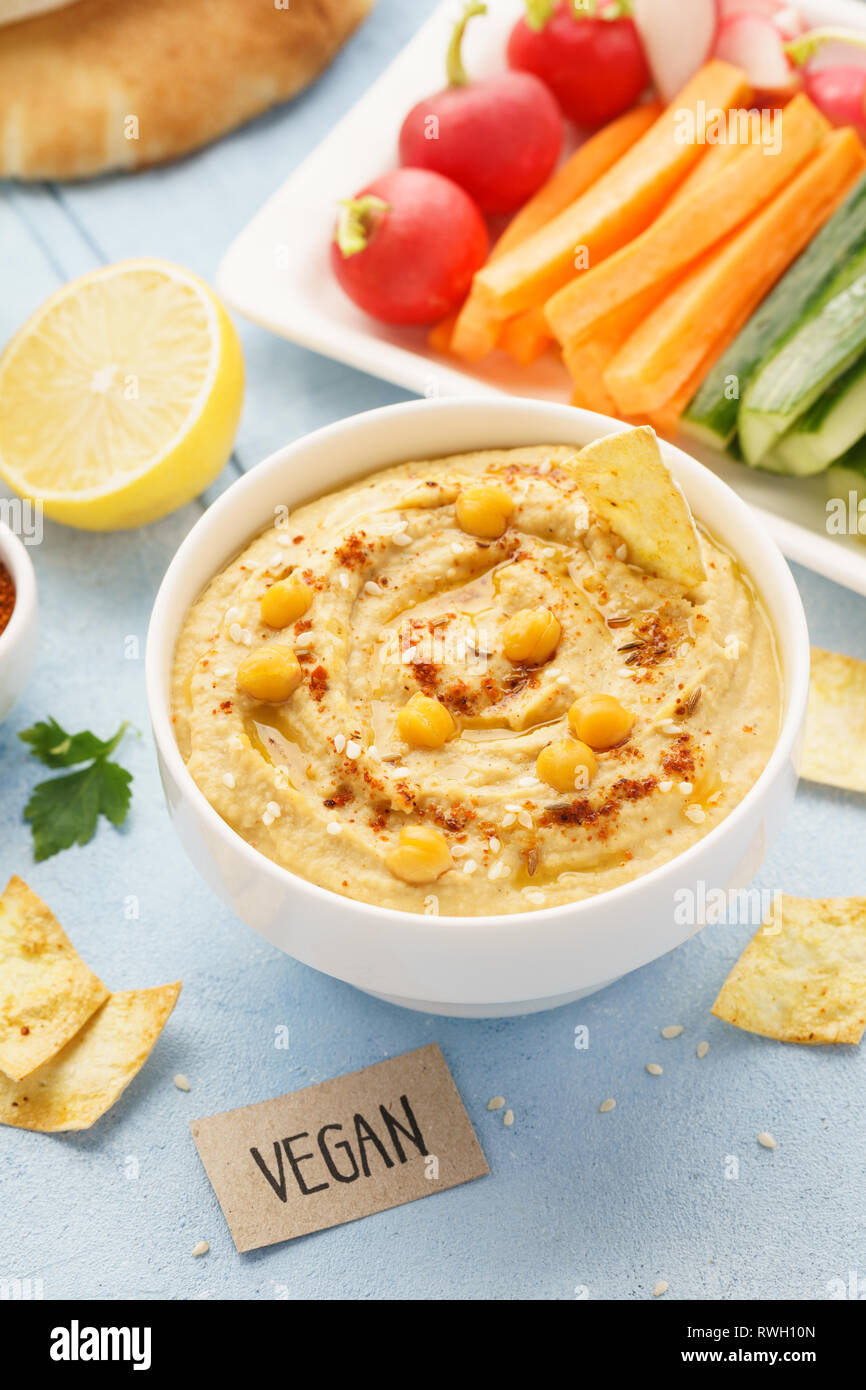 Homemade hummus with olive oil, fresh vegetable sticks and chips. Vegan