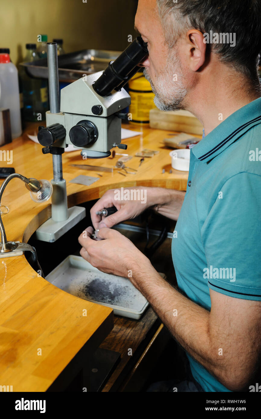 Craft jewelry making. The jeweler is looking into a microscope and