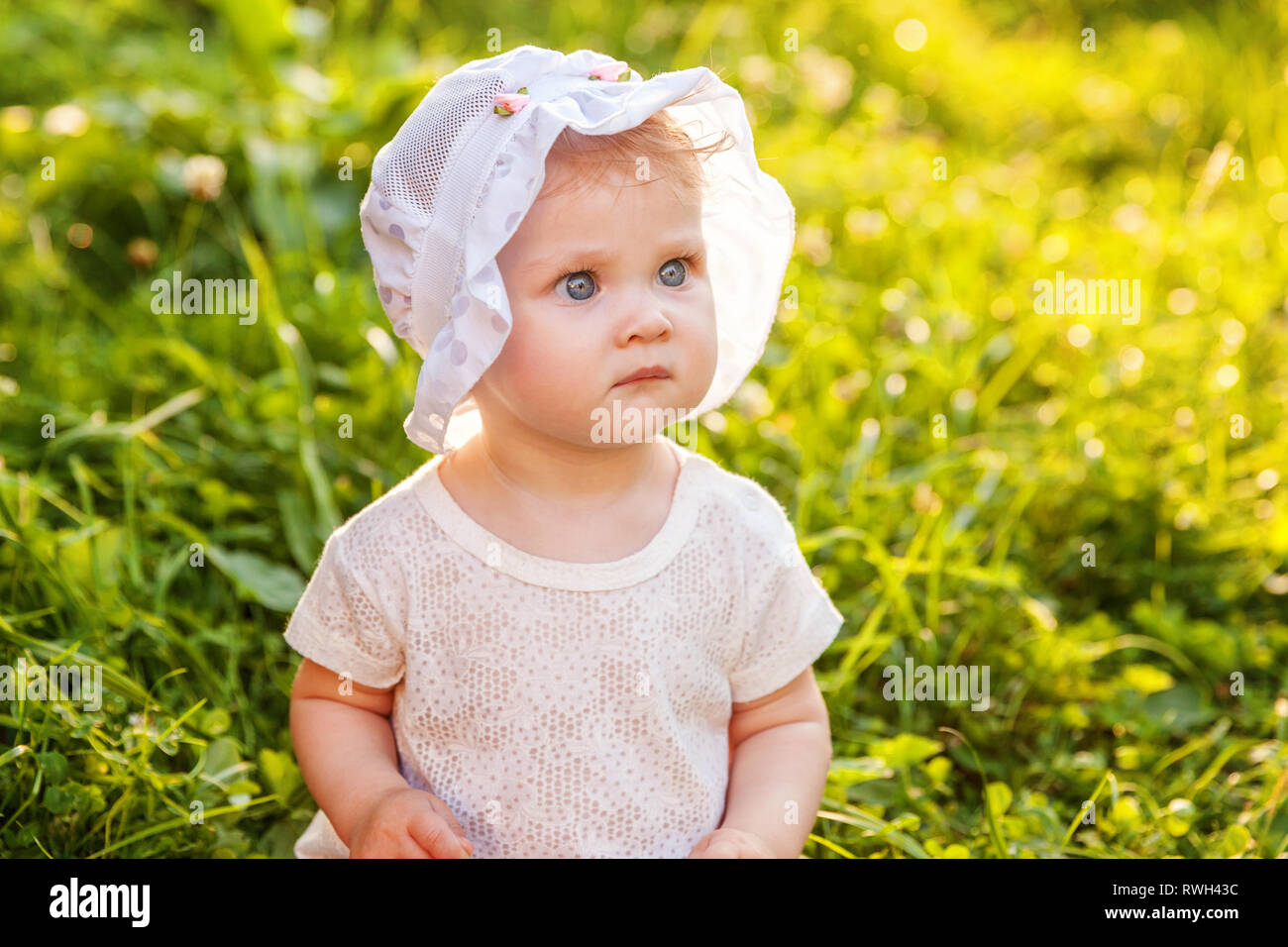 Sweet happy little baby girl sitting on grass in park, garden, meadow ...