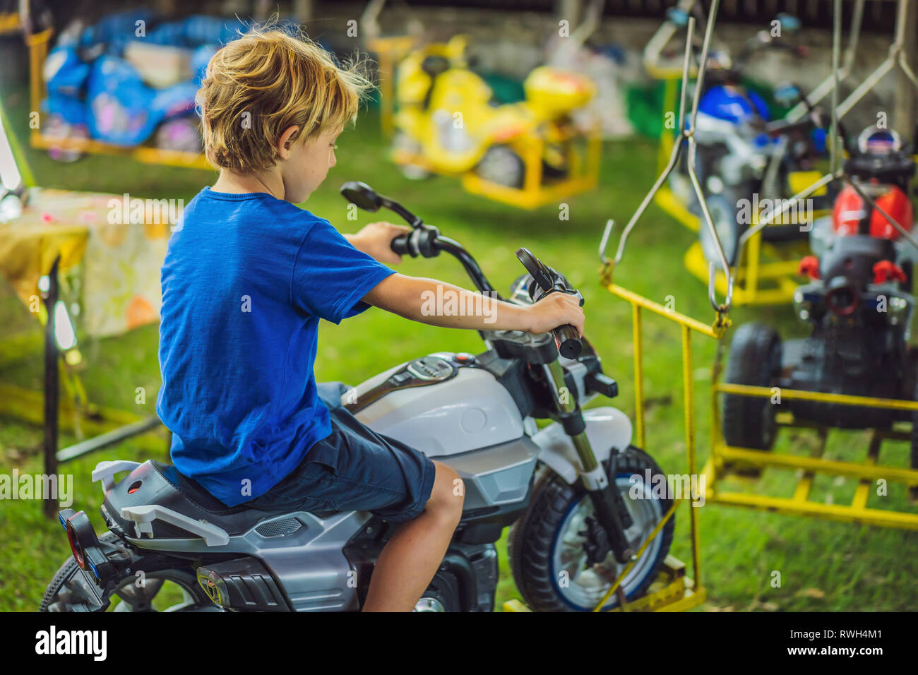 Children going on Merry Go Round, kids play on carousel in the summer Stock Photo