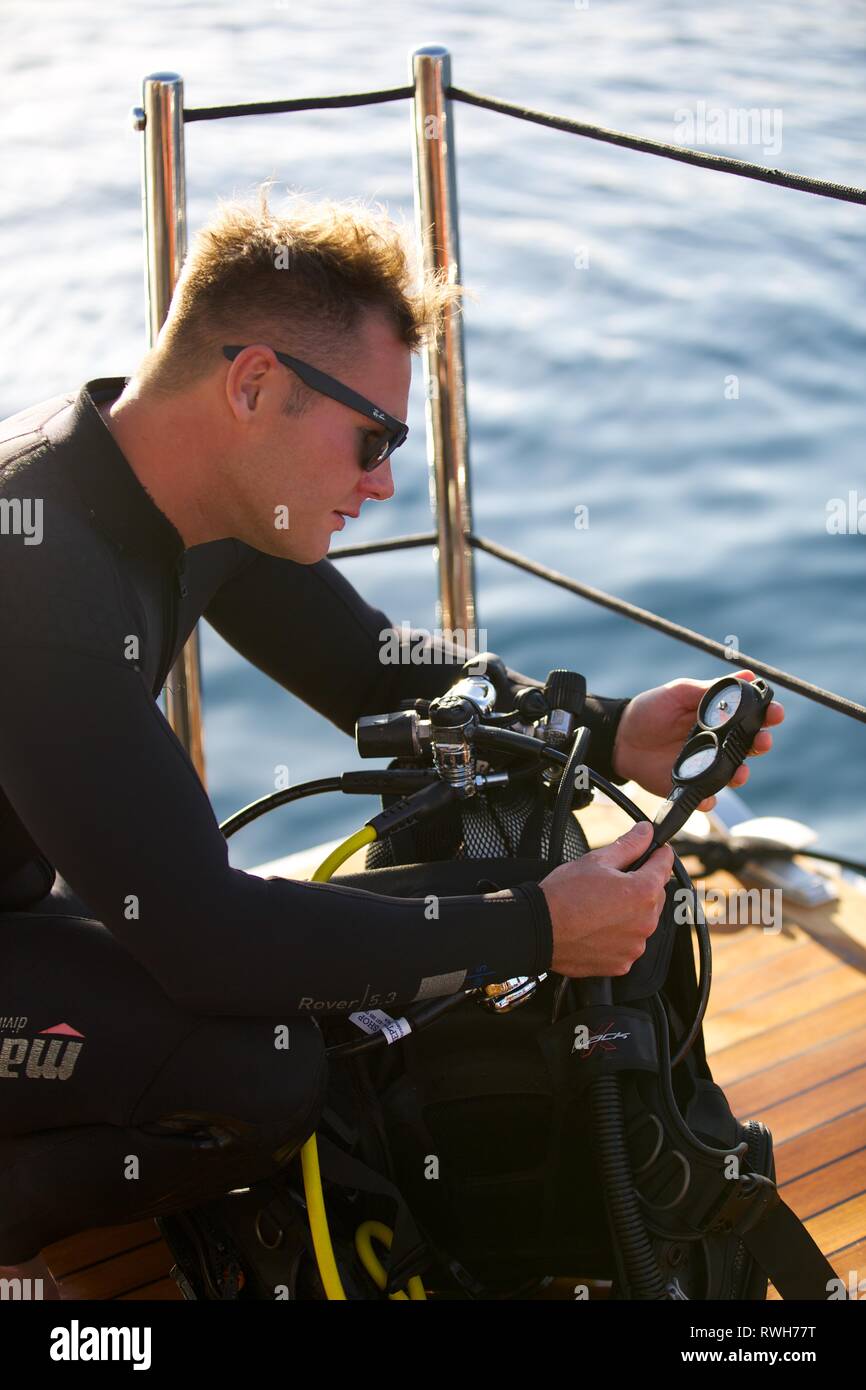 Scuba diver checks oxygen gauge on deck before dive Stock Photo
