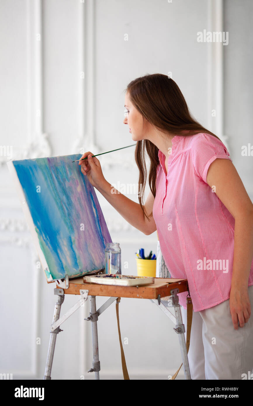 Female artist with brush and paint palette on color background. Stock Photo