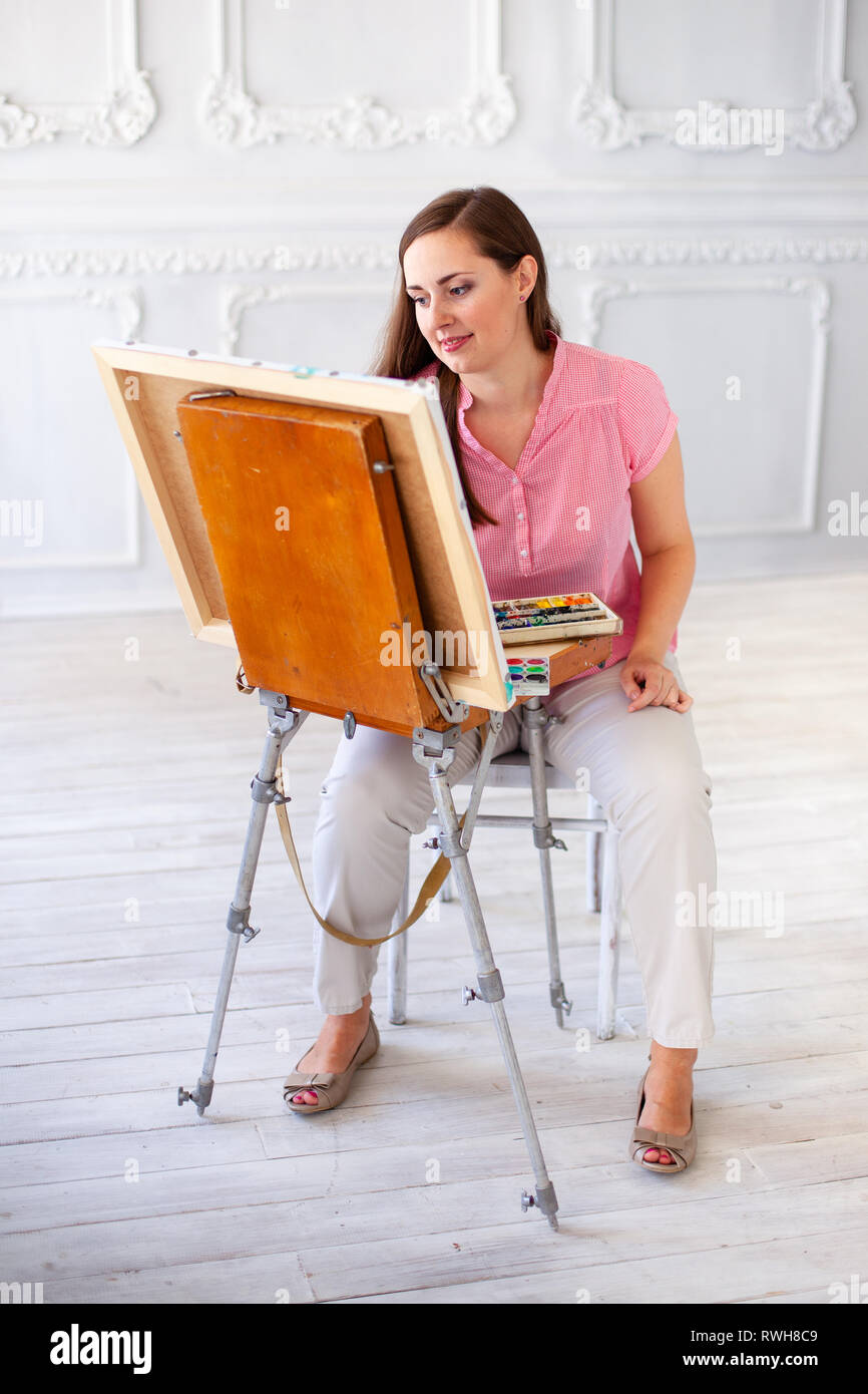 Female artist with brush and paint palette on color background. Stock Photo