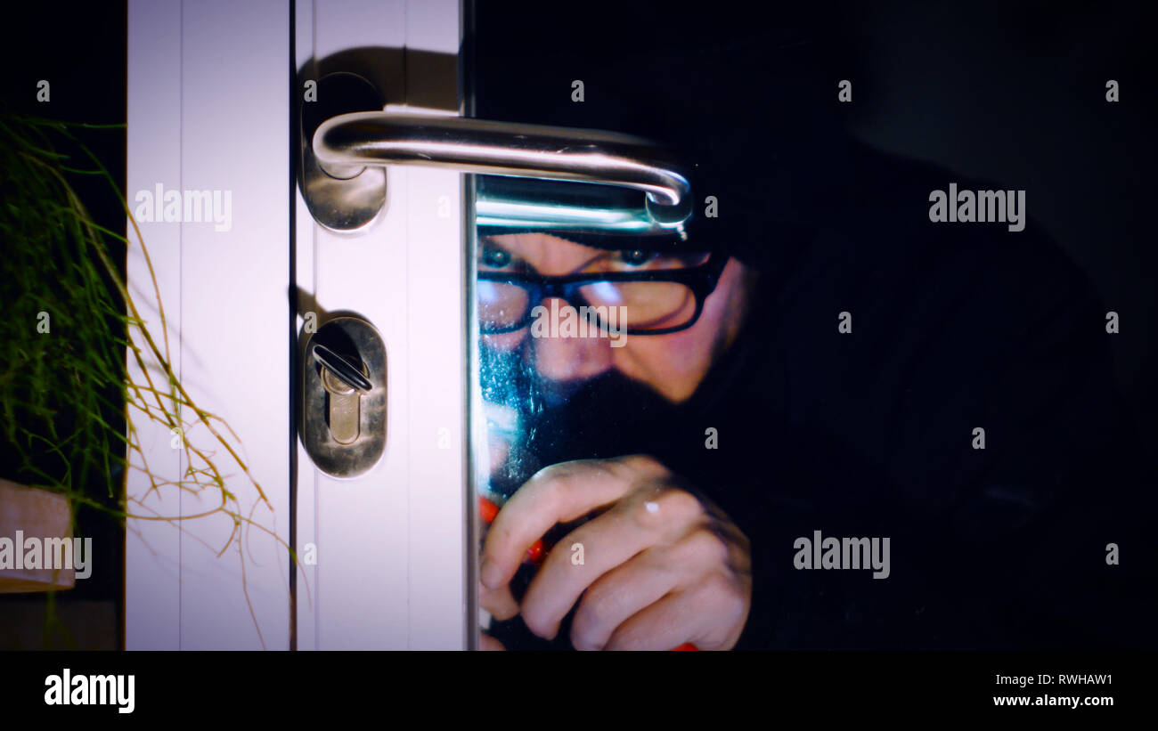 burglar enters the house, breaking through the glass door with