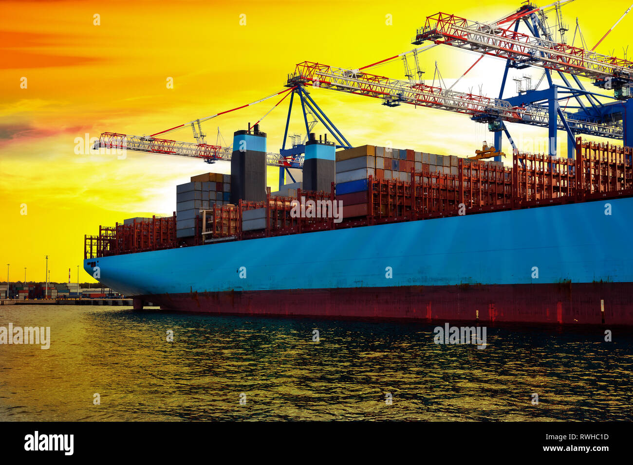 Container ship in port under loading at sunrise. Stock Photo