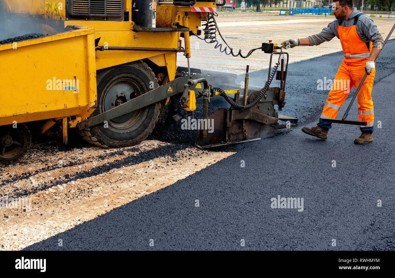 Machine operator to spread asphalt, intervenes on the control panel to adjust the asphalt paving Stock Photo