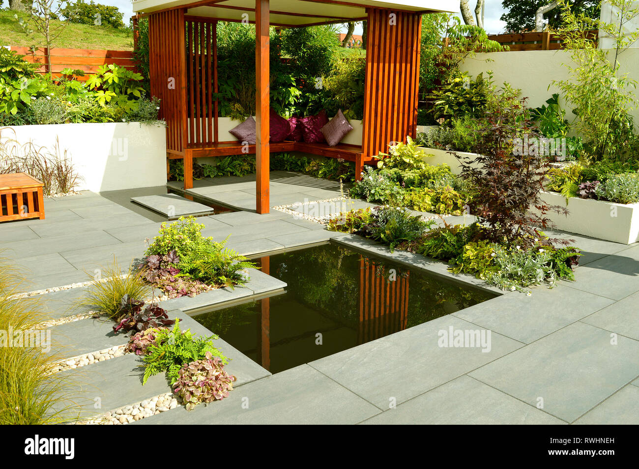 Low maintenance garden with a stone patio and ornamental garden pond Stock Photo