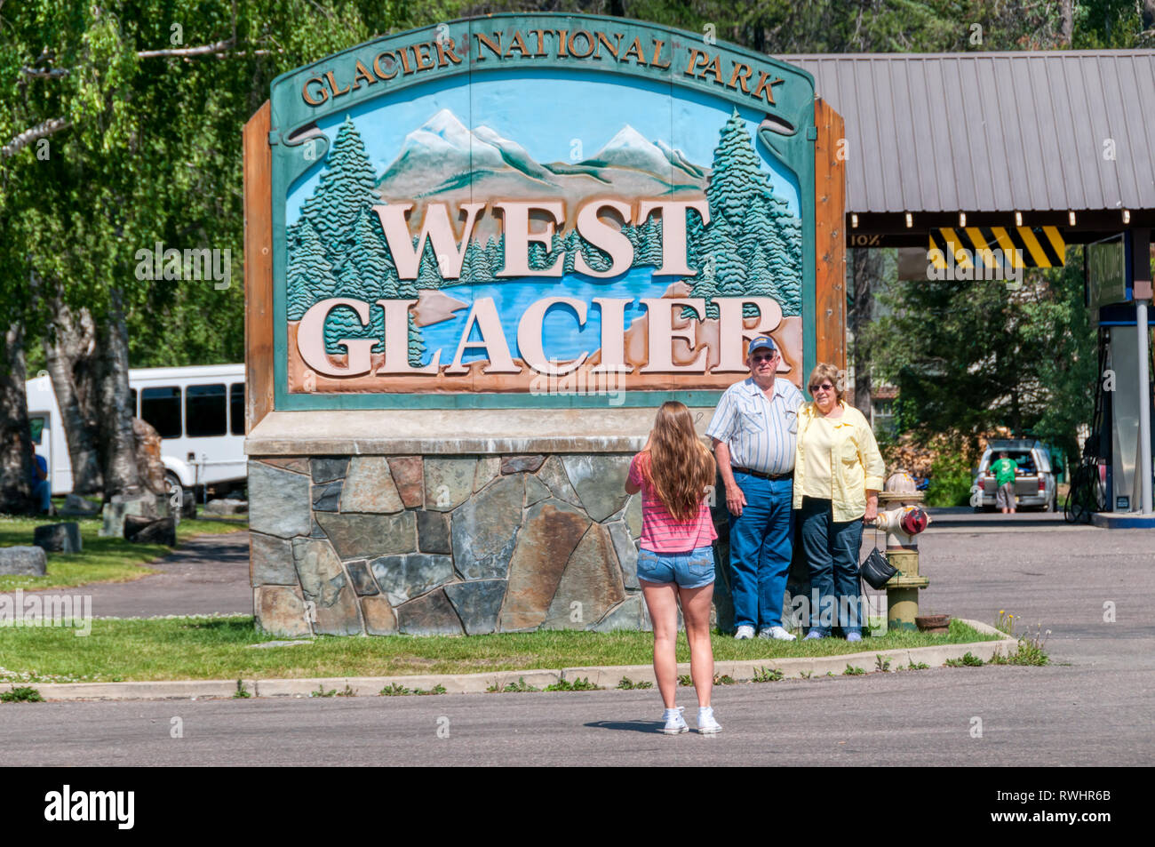 Tourists taking a photograph against the sign at the West Glacier entrance to Glacier National Park, Montana, USA Stock Photo