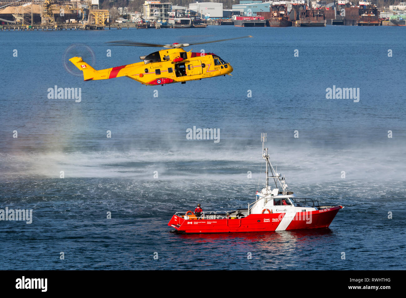 A Royal Canadian Air Force CH-148 Cormorant Helicopter hovers above a Fisheries and Oceans Canada boat during a training exercise in Vancouver Harbour, British Columbia, Canada. Stock Photo