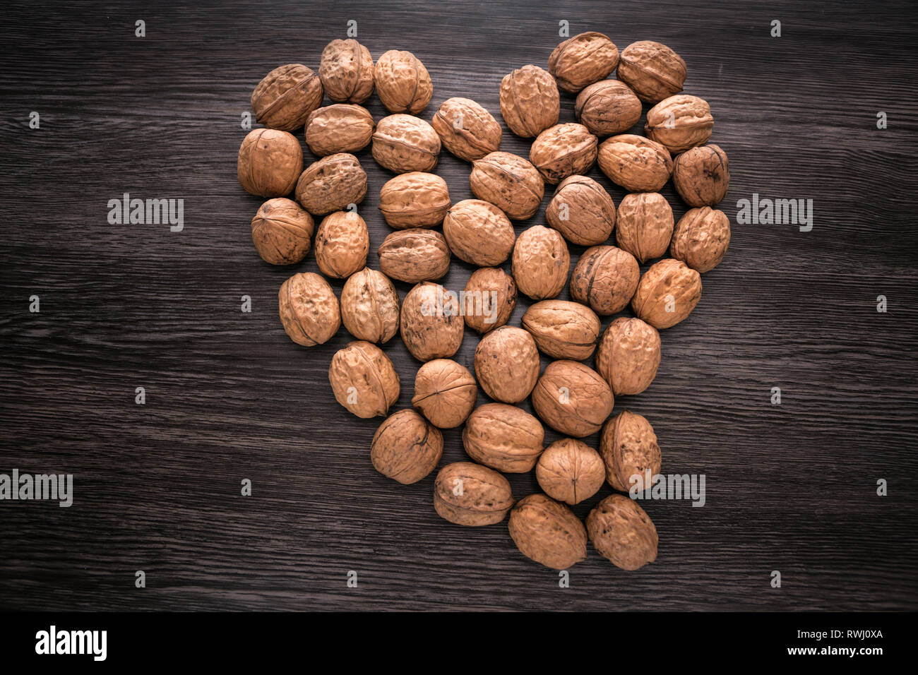 Sign Heart lined with raw walnuts on wood background. Walnut heart