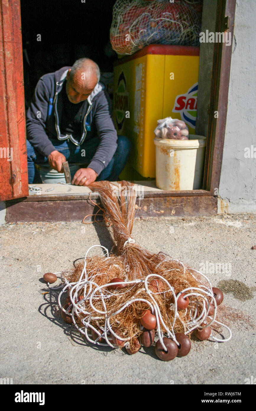 Fisherman repairing fishing net with cords and floats Stock Photo Alamy