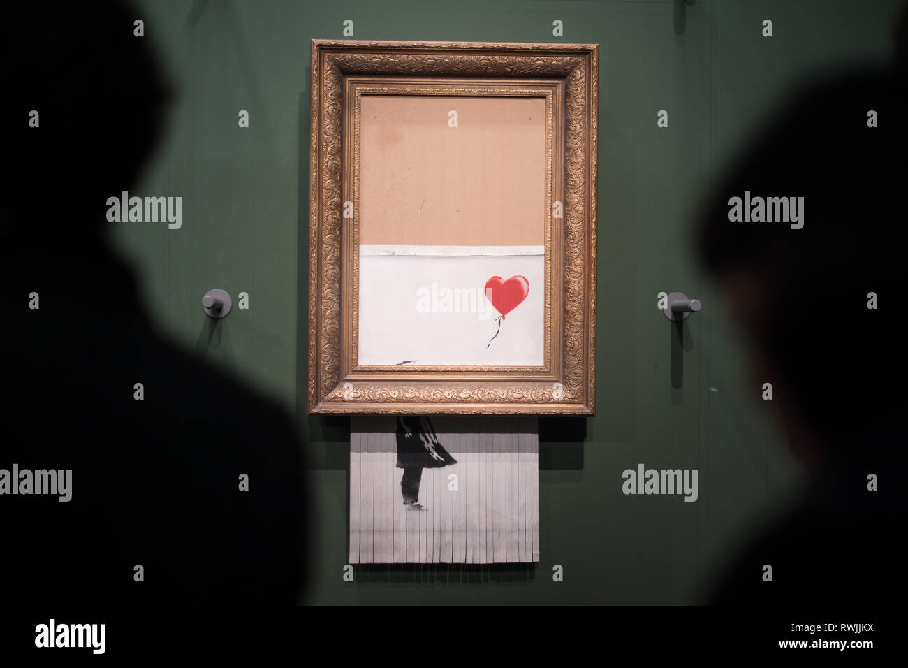 Stuttgart, Germany. 07 March 2019, Baden-Wuerttemberg, Stuttgart: Visitors stand in front of the shredded Banksy picture 'Love is in the Bin' in the Staatsgalerie. The painting is on loan to the museum from an unknown collector. Initially, it is limited to one year. Originally the picture had the title 'Girl with Balloon'. Since it destroyed itself during an art auction in London, it has been called 'Love is in the Bin'. Credit: dpa picture alliance/Alamy Live News Stock Photo