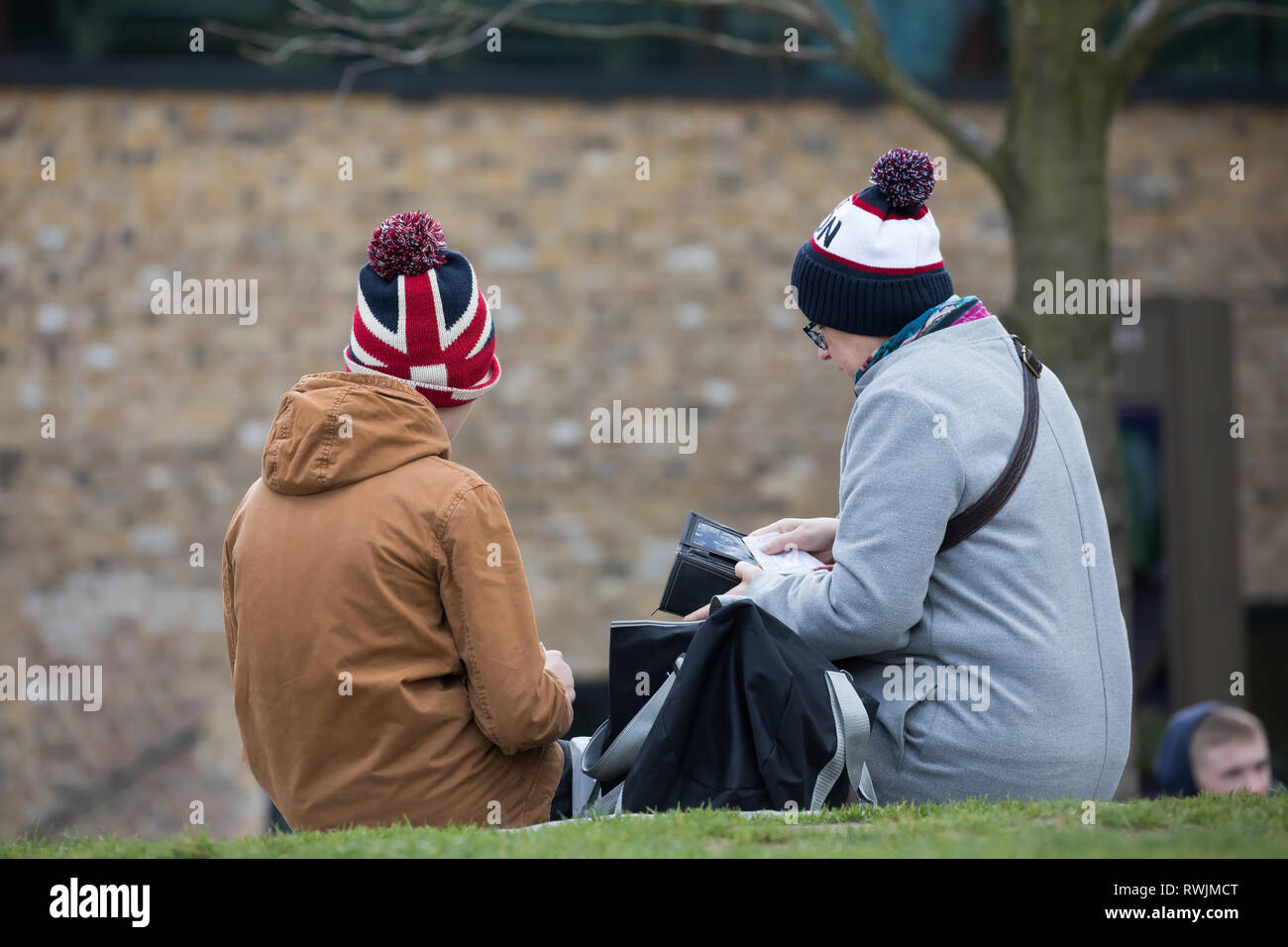 London, UK. 7th Mar, 2019. People sitting down on the Queenswalk in London enjoying the sunshine and River views wearing bobble hats. Strong winds are forecast for this afternoon in London again. Credit: Keith Larby/Alamy Live News Stock Photo
